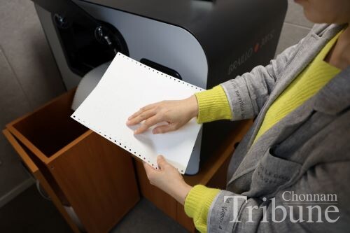 Braille transcriber Kim checks the accuracy of a braille tranｓｃｒｉｐｔion.