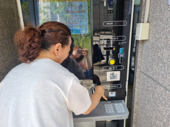지난 8월 화정2동행정복지센터에 있는 BF 무인민원발급기를 사용하고 있는 강경화씨가 지문 인식 부분에 손을 대기 어려워하고 있다. 장애인권익옹호기관 제공.